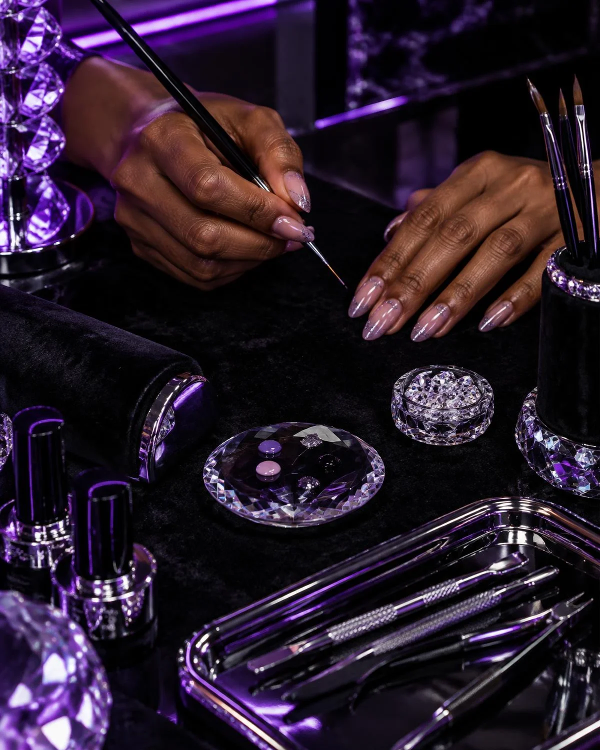 Illustrative artist hands holding a fine brush at a nail workstation, not Danielle