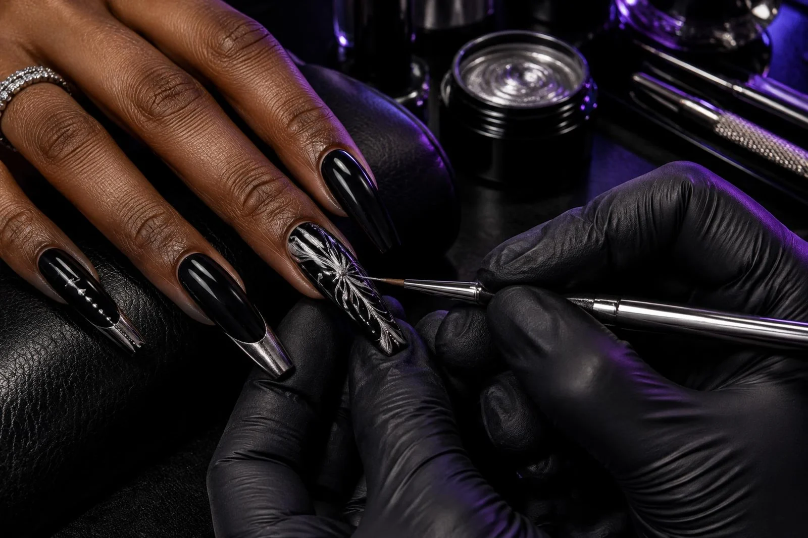 Illustrative fine brush painting silver details on a black nail